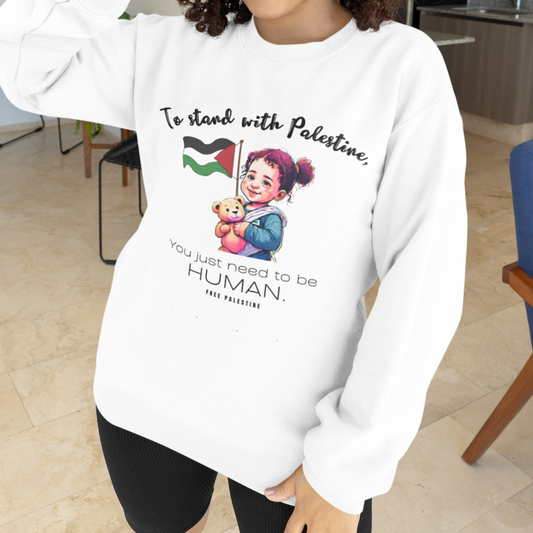 Person wearing a white sweatshirt with a graphic and text, standing in a modern indoor setting.