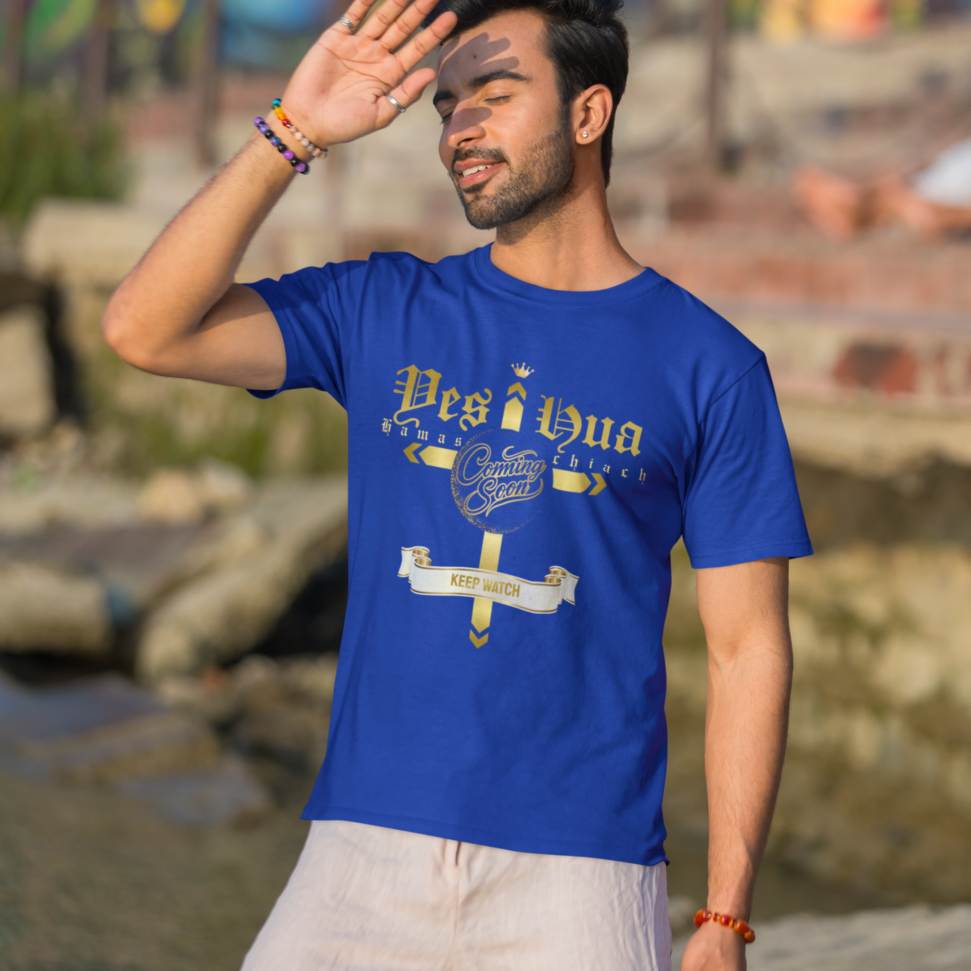 Man wearing a blue t-shirt with text and graphics, standing outdoors with a colorful mural in the background.