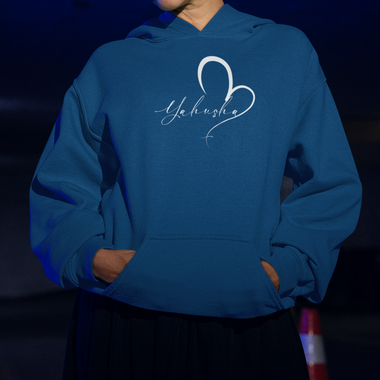 Person wearing a blue hoodie with a logo, standing against a dark background.