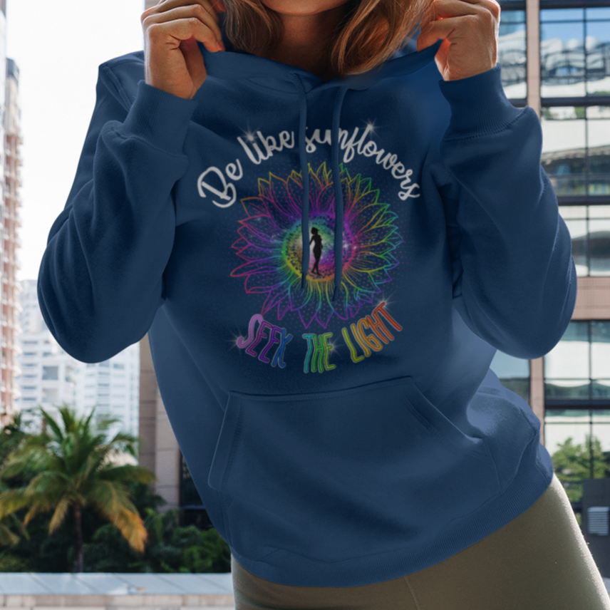 Woman holding a blue hoodie with colorful design and text in an urban setting