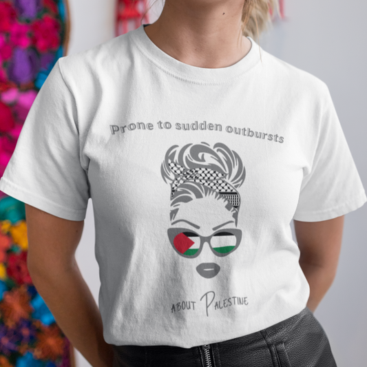 Person wearing a white t-shirt with a graphic design and text, standing against a colorful floral wall.