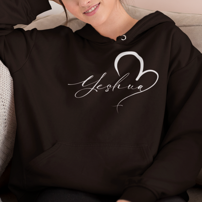 Woman wearing a black hoodie with 'Yeshua' design, sitting on a couch.