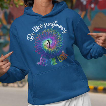 Woman wearing a blue hoodie with a colorful design and text, standing in front of a mural.