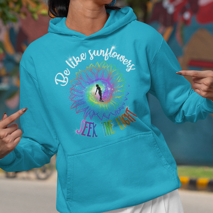 Woman wearing a blue hoodie with colorful design and text, standing in front of a mural.