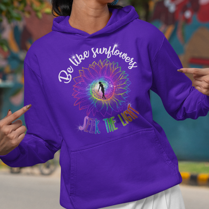 Woman wearing a purple hoodie with a colorful design and text, standing in front of a mural.