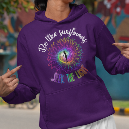 Woman wearing a purple hoodie with a colorful design and text, standing in front of a mural.