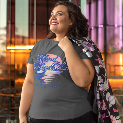 Woman wearing a gray t-shirt with colorful graphics and text, standing outdoors.
