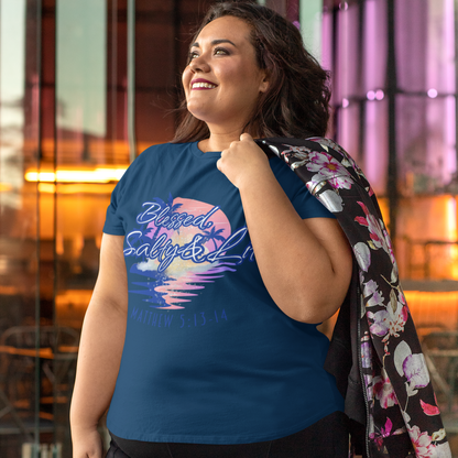 Woman wearing a blue t-shirt with colorful graphics and text, standing outdoors.