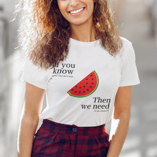 Woman wearing a white t-shirt with a watermelon graphic and text, standing outdoors.