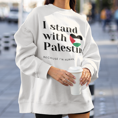 Person wearing a white sweatshirt with 'I stand with Palestine' text on a city street.
