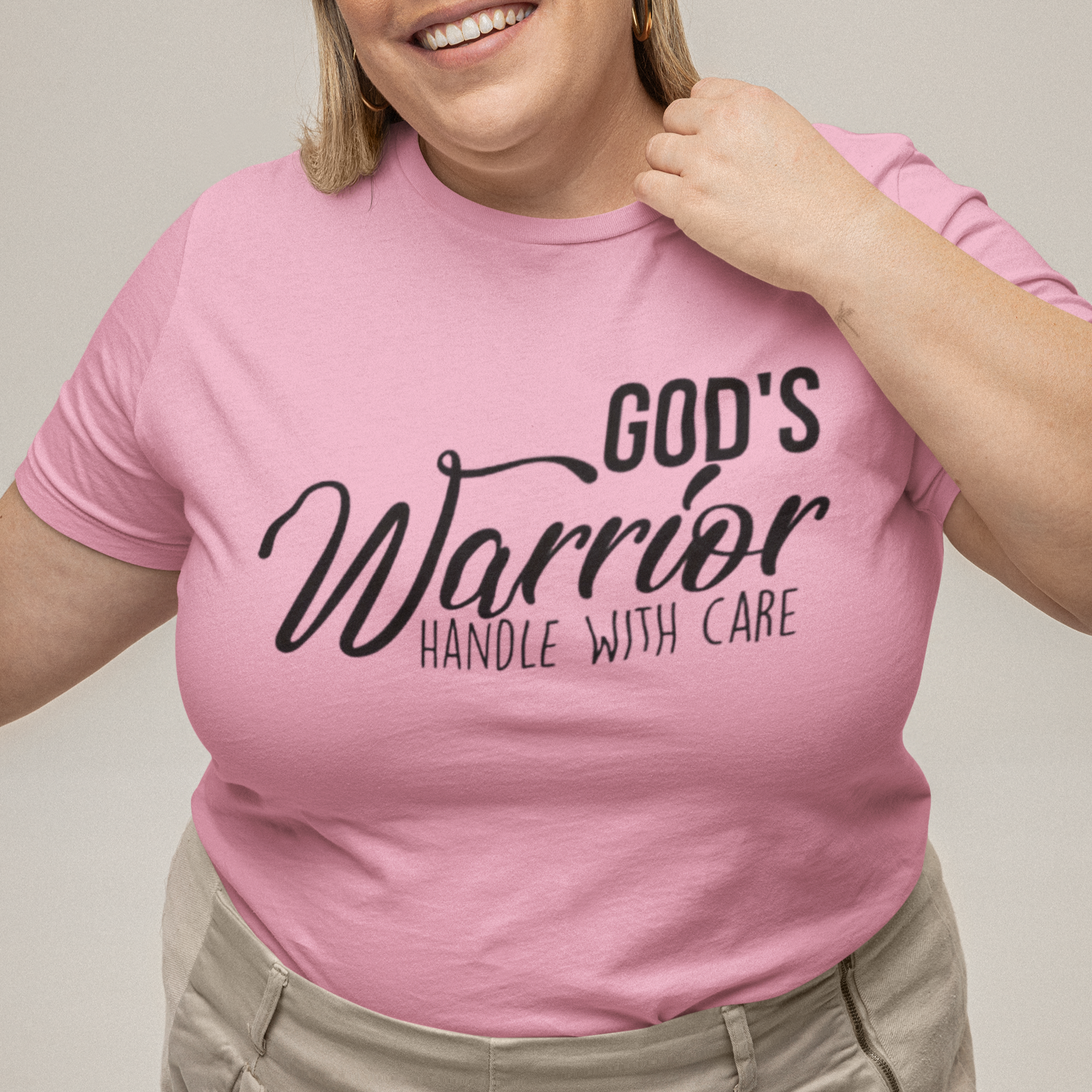 Person wearing a pink t-shirt with text, standing against a plain background