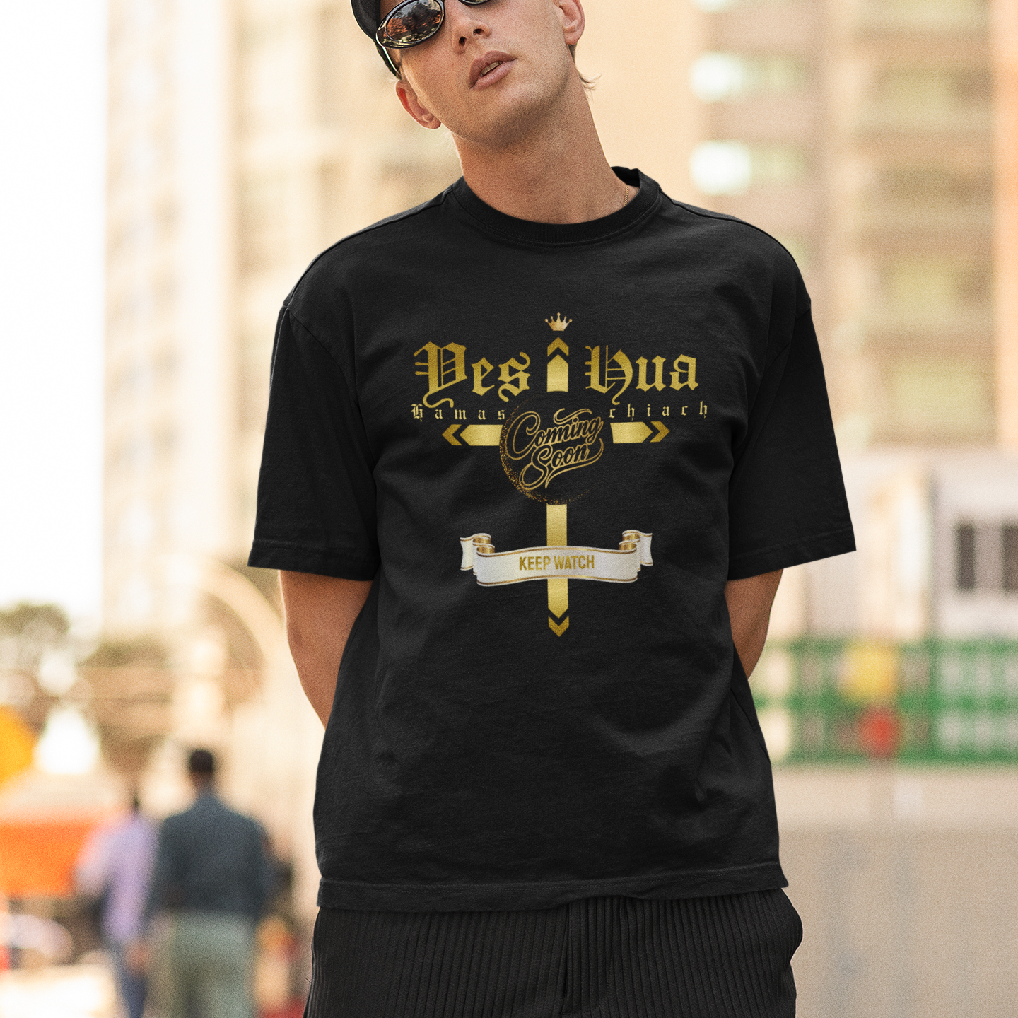Man wearing a black t-shirt with gold text and sunglasses, standing outdoors.