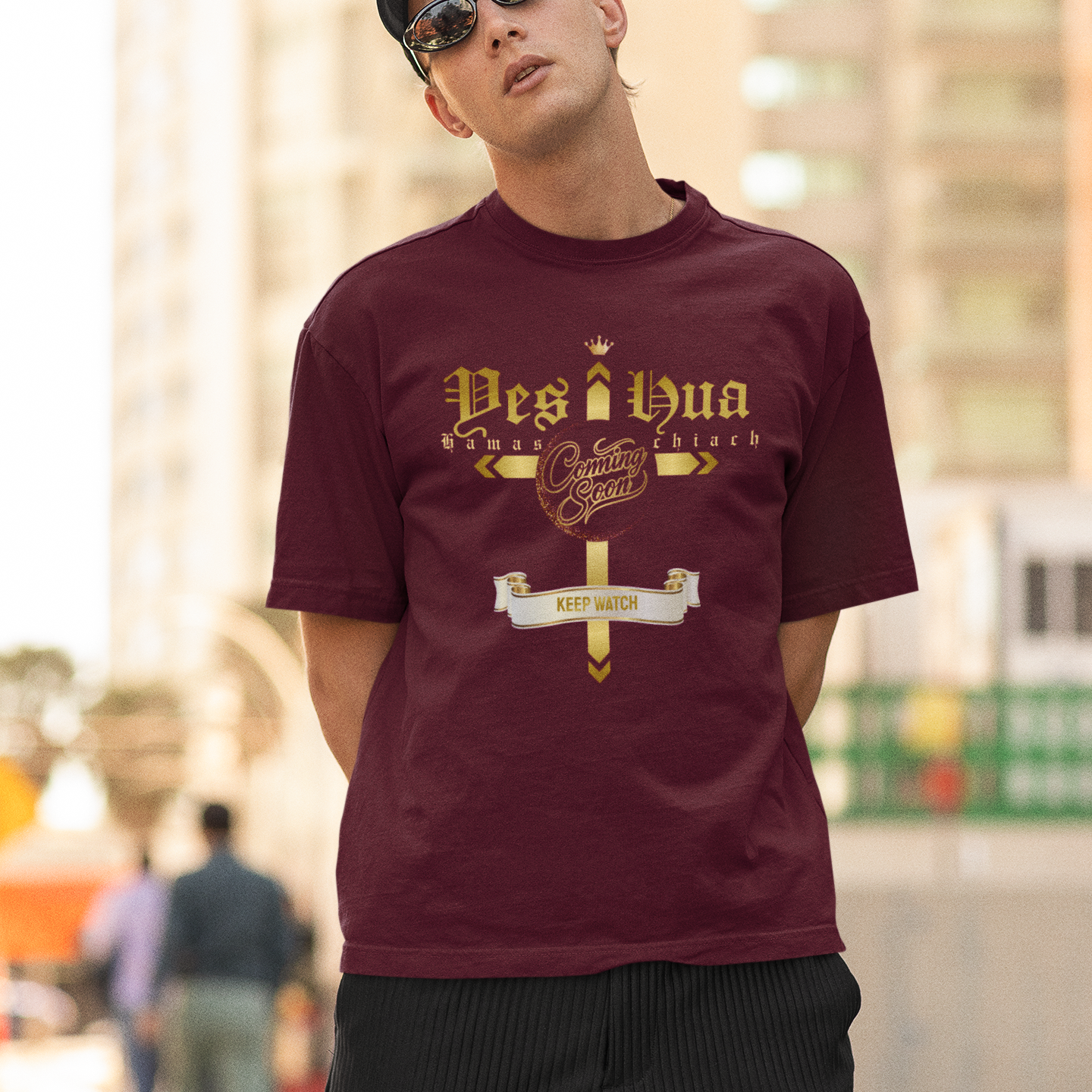 Man wearing a maroon t-shirt with text and graphics, standing outdoors.