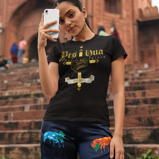 Person taking a selfie wearing a black t-shirt with 'Desi i Hua' design in front of a brick building.