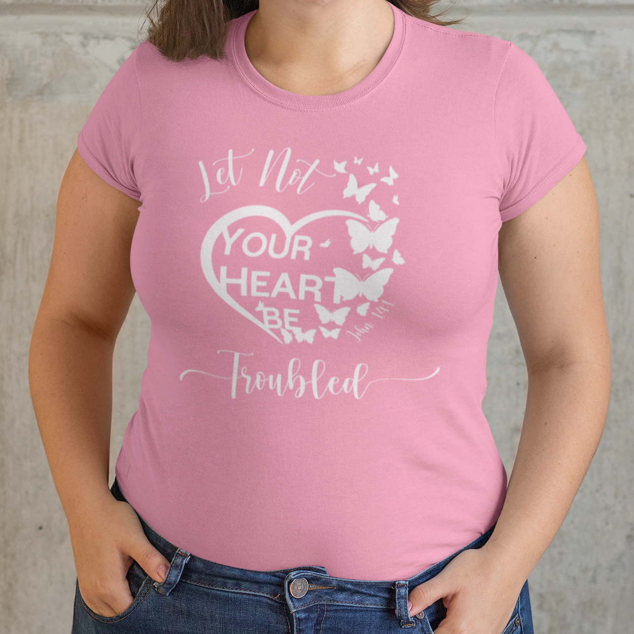 Woman wearing a pink t-shirt with text and butterfly design against a neutral background