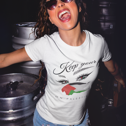 Woman wearing sunglasses and a white t-shirt with graphic design, standing among metal barrels.