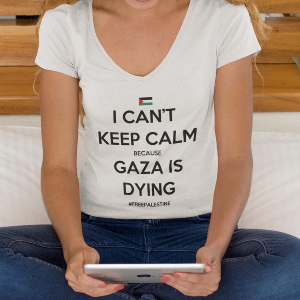 Woman sitting on a bed wearing a t-shirt with a message about Gaza, using a tablet.