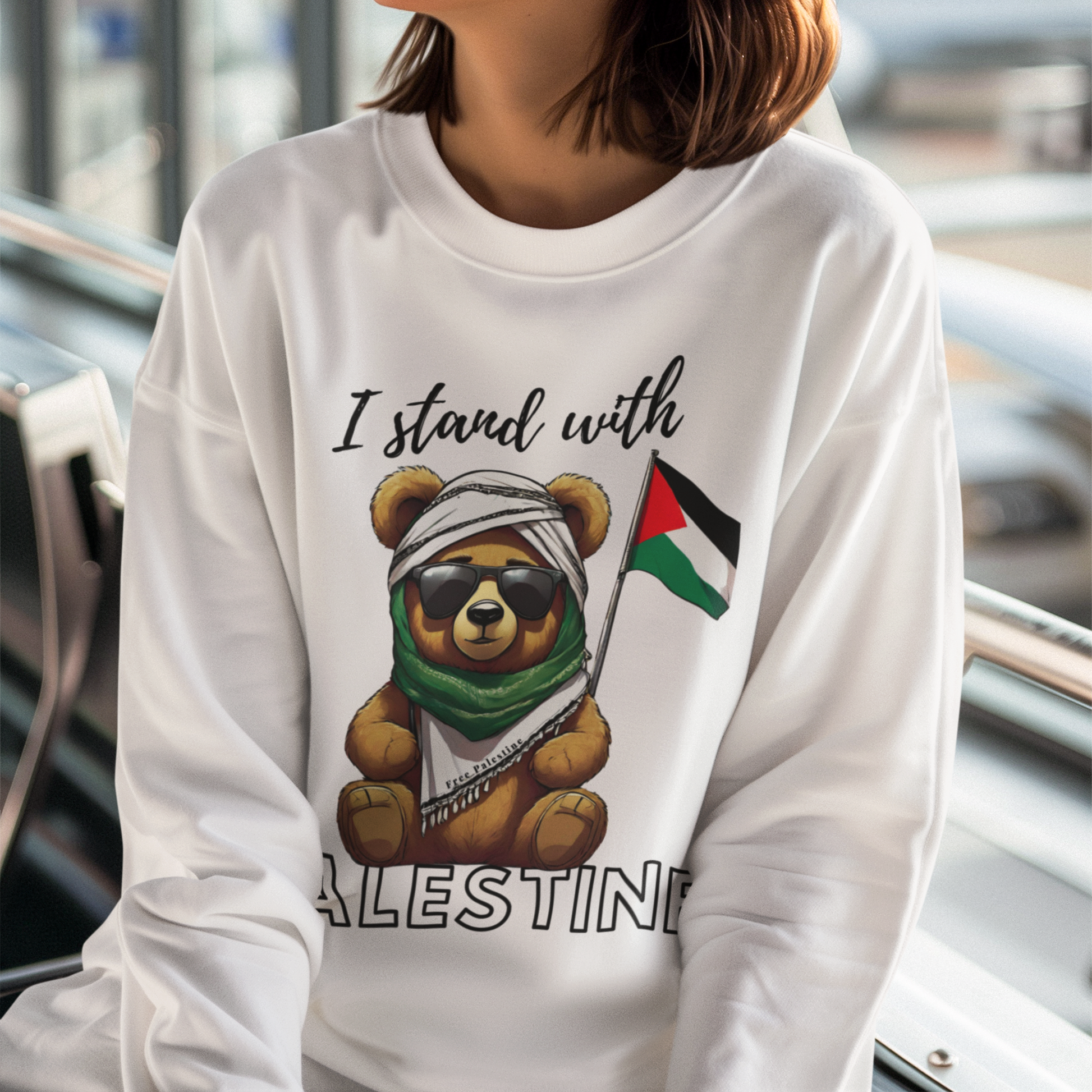 Woman wearing a white sweatshirt with a bear holding a Palestinian flag and 'I stand with Palestine' text.