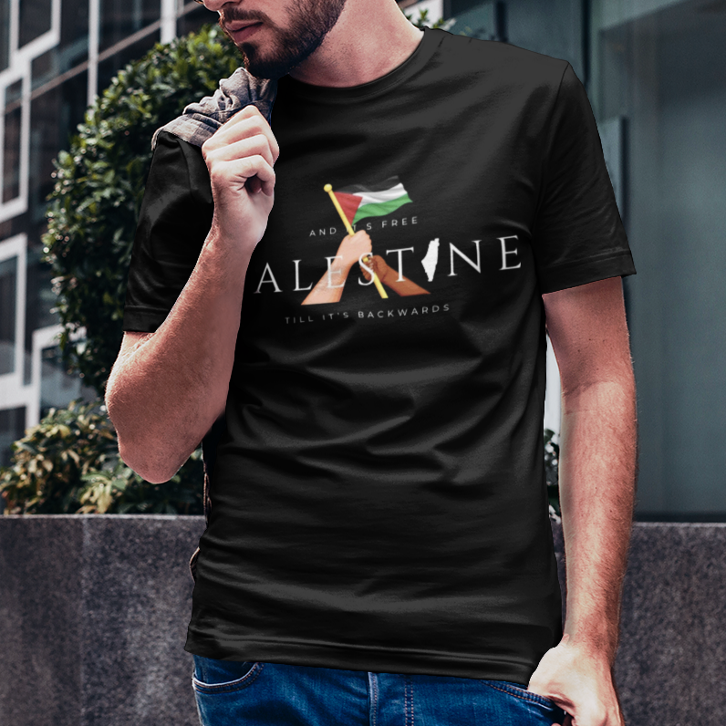 Man wearing a black t-shirt with a logo and text, standing in an urban setting.