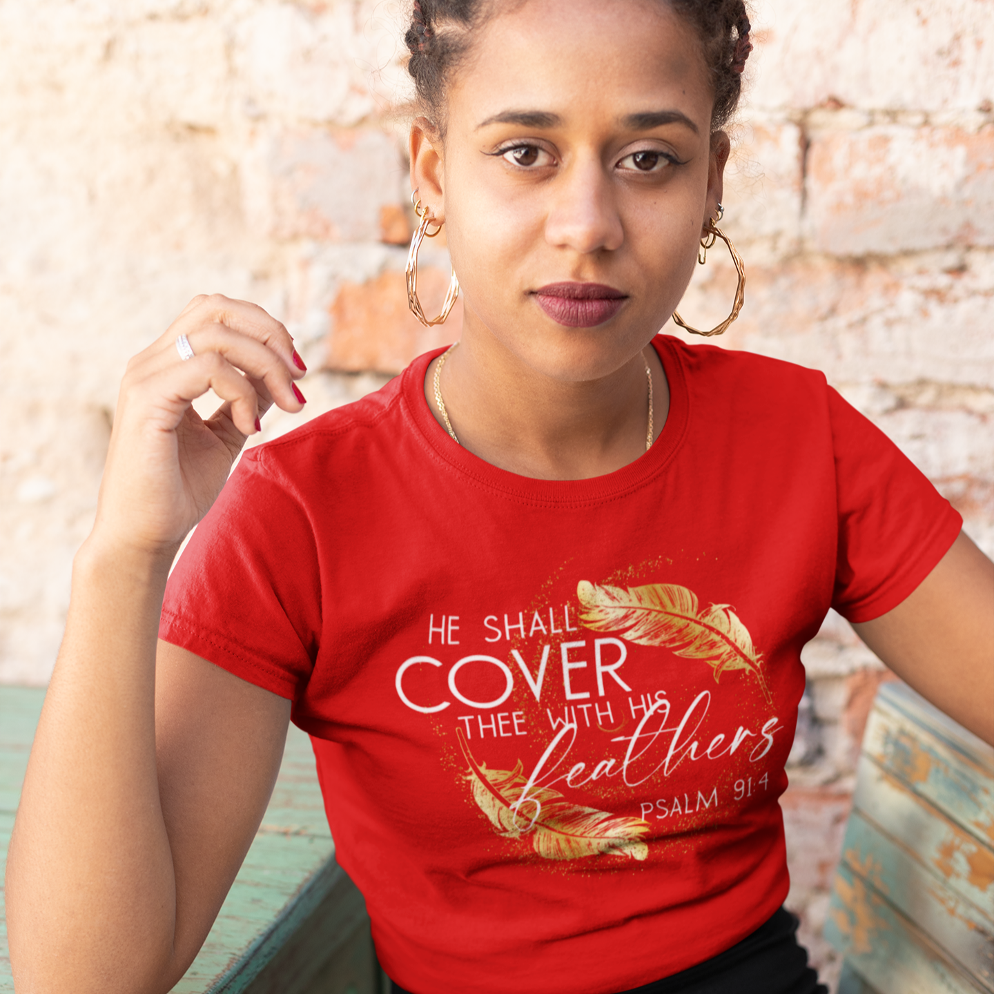 Woman wearing a red t-shirt with a quote, sitting outdoors.