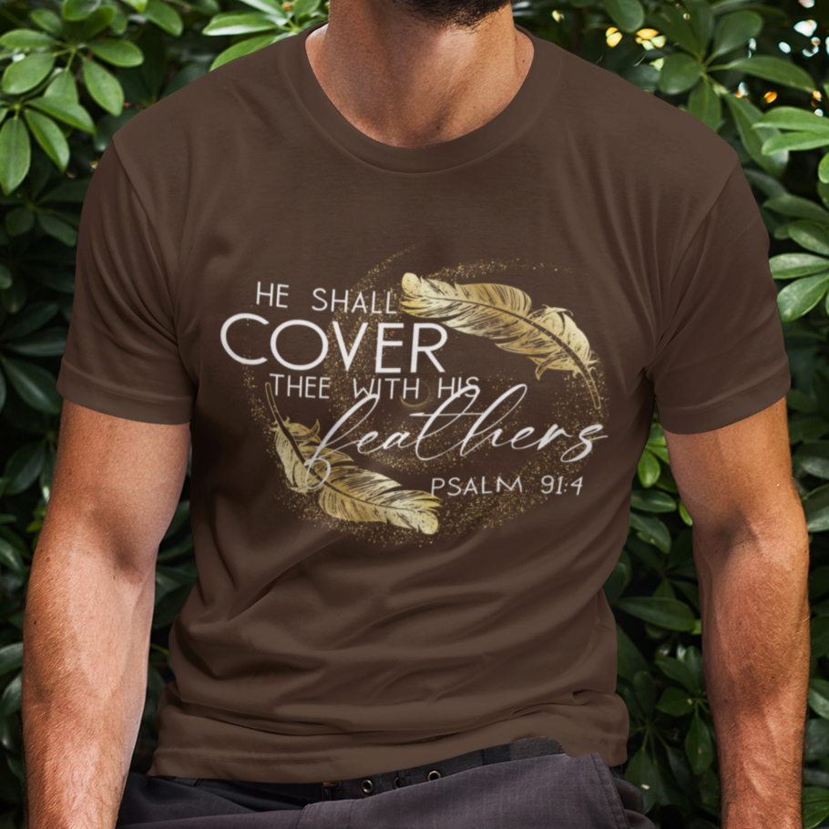 Man wearing a brown t-shirt with a design and text, sitting against green foliage.