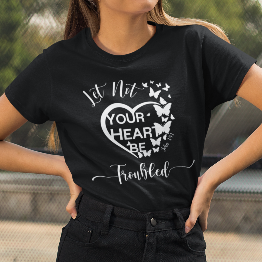 Woman wearing a black t-shirt with a heart design and text outdoors.