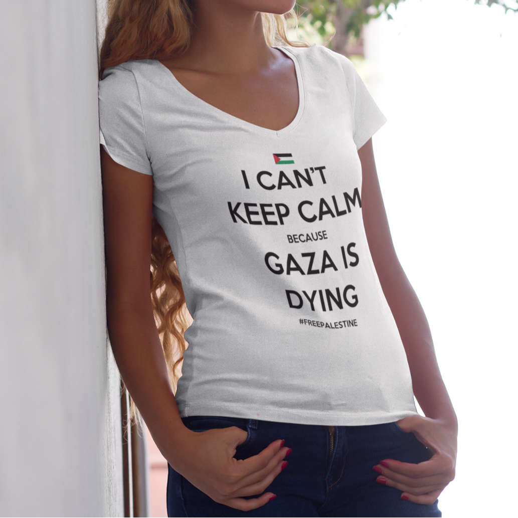 Woman wearing a white t-shirt with a message about Gaza, standing against a light-colored wall.