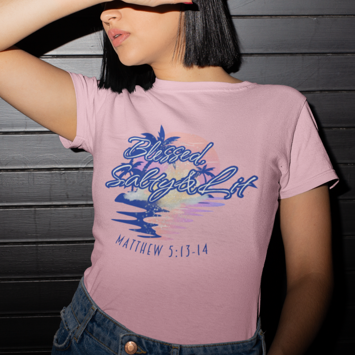 Person wearing a pink t-shirt with a colorful design and text against a dark wooden background